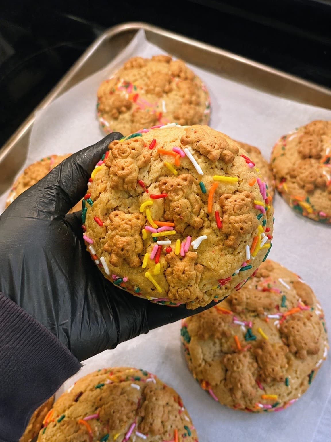 Sugar Spell loaded frosted animal cookie held over a baking tray