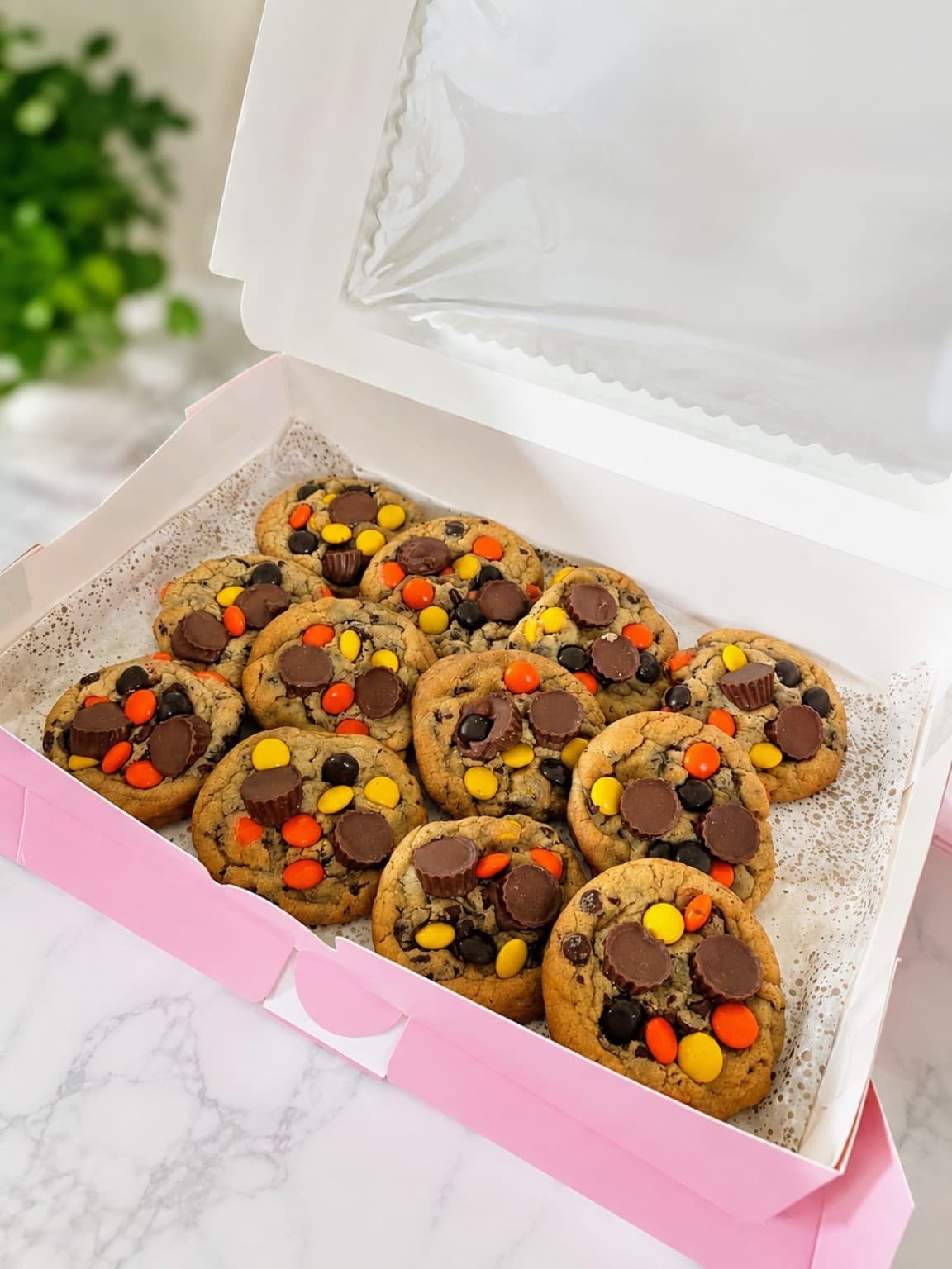 Open pink box filled with loaded Reese's Pieces cookies