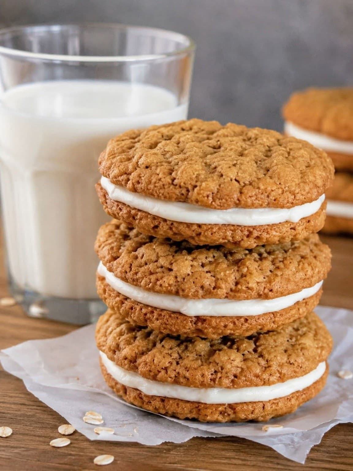 Stack of oatmeal cream pies with sweet cream filling beside a glass of milk